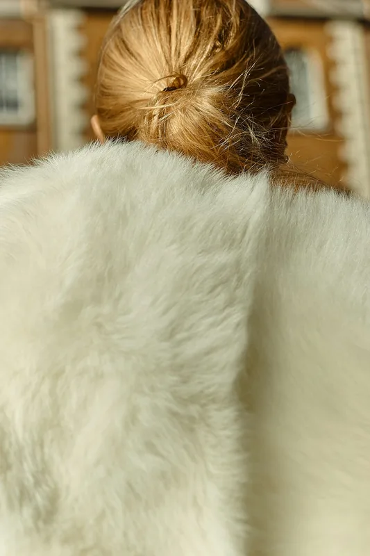 Mujer de espaldas con una estola de pelo color marfil